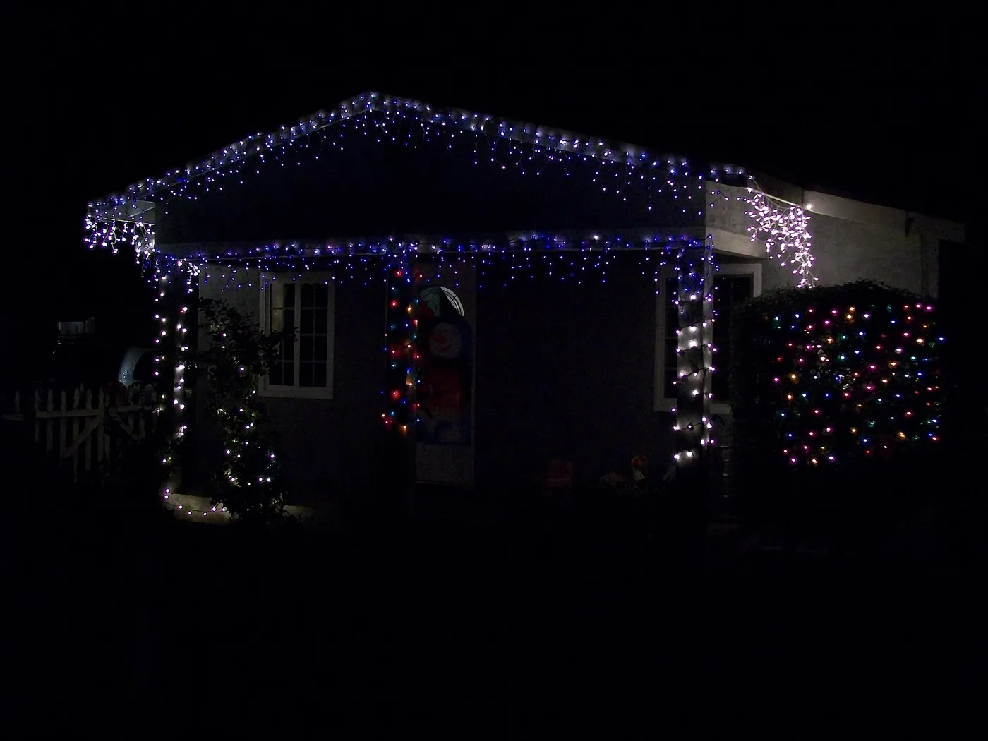 Roofline and porch lit with white and blue Christmas lights